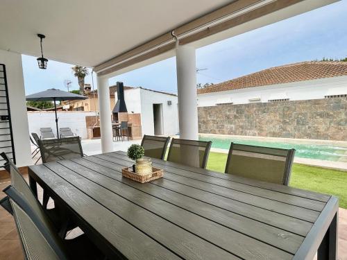 a wooden table and chairs on a patio at Modern 3-Bedroom Villa with Private Pool & BBQ in Cádiz