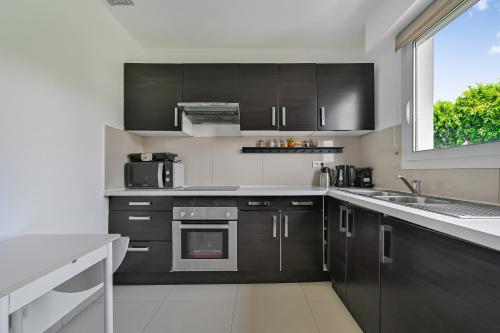 une cuisine avec des armoires noires et une fenêtre dans l'établissement Le City Mood - 2 pers - Wifi - Stade de France, à Aubervilliers