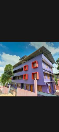 a purple building with red windows and a tree at Finenest homes kalpetta in Kalpetta