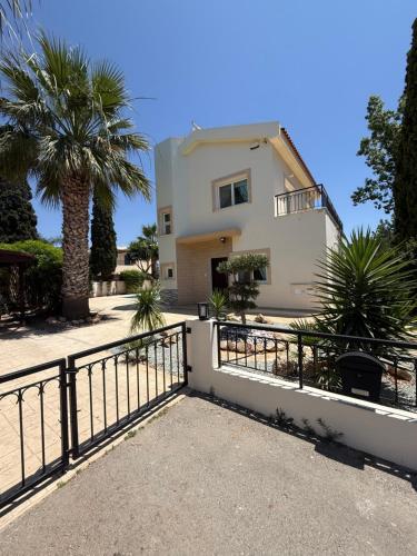 a house with a fence and a palm tree at Villa Porta Aurea in Ayia Napa