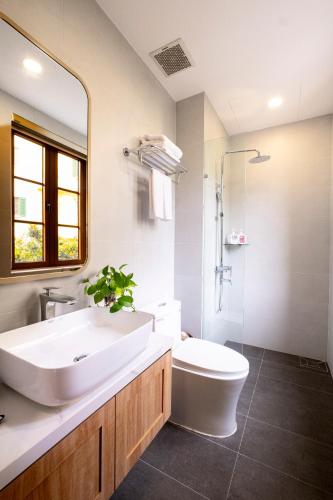 a bathroom with a sink and a toilet and a mirror at Jana Hotel & Apartment - Firework & Aquatopia Water Park in Phu Quoc