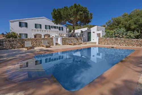 a pool with chairs and a house in the background at Agroturismo Santa Mariana in Alaior