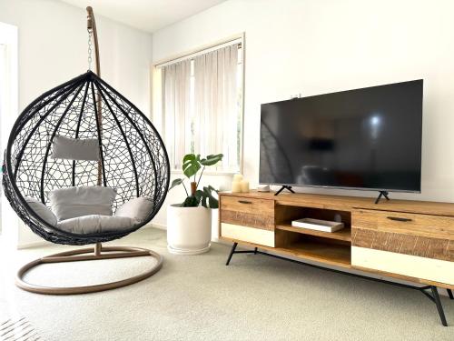 a living room with a hanging chair and a television at Large warm 4BRM family recharge in Halswell - Netflix, Massage chair in Halswell