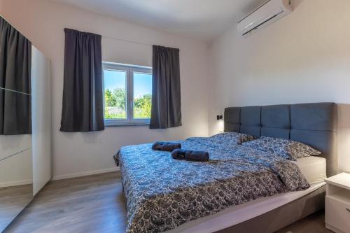 a bedroom with a bed with a blue comforter and two windows at E&M Forest Retreat in Svetvinčenat