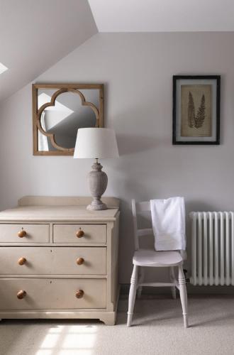 a bedroom with a dresser and a lamp and a chair at Shepherds Cottage, Pentland Hills in Nine Mile Burn