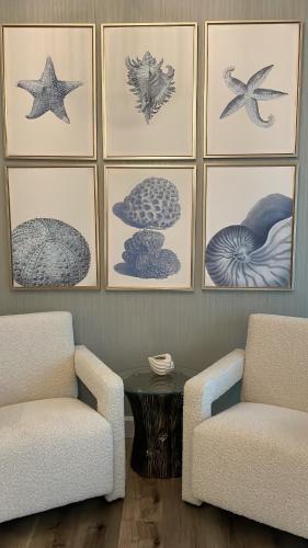a living room with two chairs and a table and pictures at Coral Holiday Home in Abu Dhabi