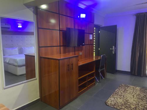 a bedroom with a large wooden cabinet and a bed at Beamgate Hotels & Apartments, Abak Rd, Uyo in Uyo