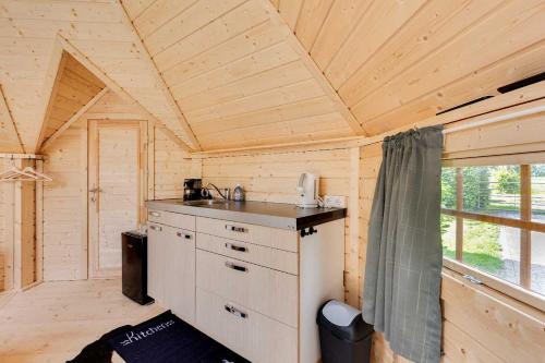 a small kitchen in a wooden cabin with a window at Gastenverblijf Belle Rose Ruurlo in Ruurlo