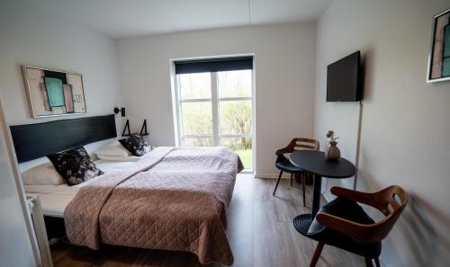 a bedroom with a bed and a table and a window at Hotel Aarslev Kro in Brabrand