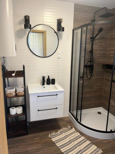 a bathroom with a shower and a sink and a mirror at Domki Rewal kalimera-sun in Rewal