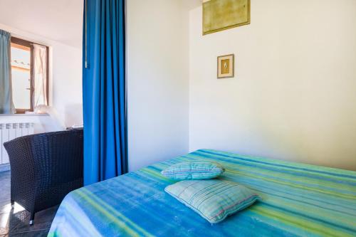 a bed with blue curtains and two pillows on it at Casa del Mandarino Gioiosa Marea in Gioiosa Marea