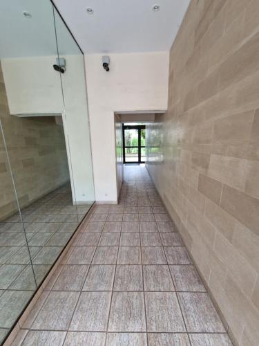 un couloir avec du carrelage et une paroi en verre dans l'établissement Charmant studio Deauville, proche plage avec parking privé, à Deauville