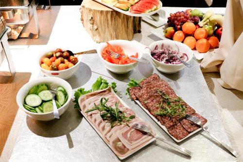 a table with plates of food and bowls of fruits and vegetables at Hotel Aarslev Kro in Brabrand