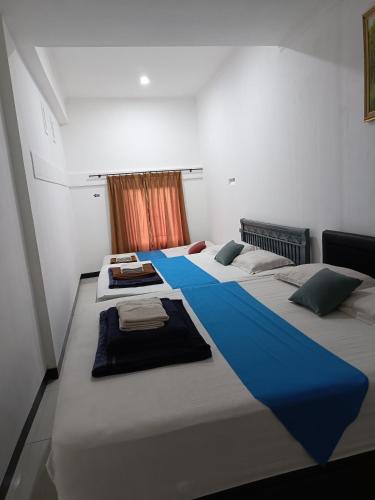 a bedroom with three beds with blue sheets and a window at Bantal Guling Villa in Lembang