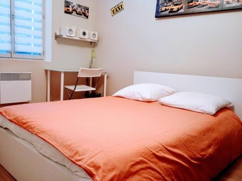 an orange bed with two pillows in a bedroom at l'Isle Contemporaine Centre ville de L'Isle sur la sorgue 74 m2 clim parking in LʼIsle-sur-la-Sorgue