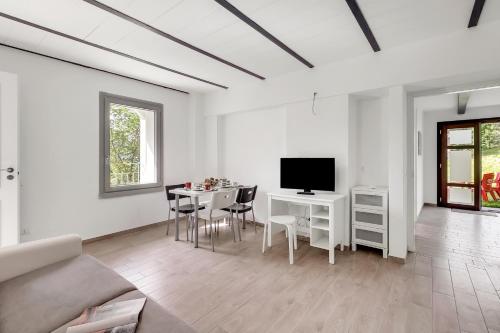 a white living room with a table and a tv at Residenza Quadrifoglio in Casalzuigno