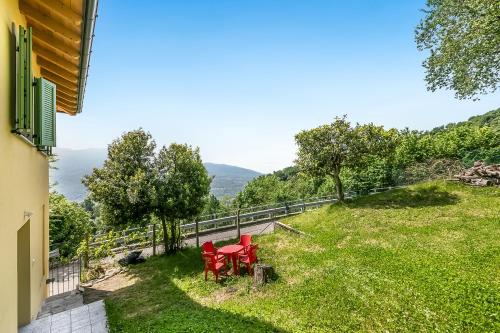 a patio with two red chairs in the grass at Residenza Quadrifoglio in Casalzuigno