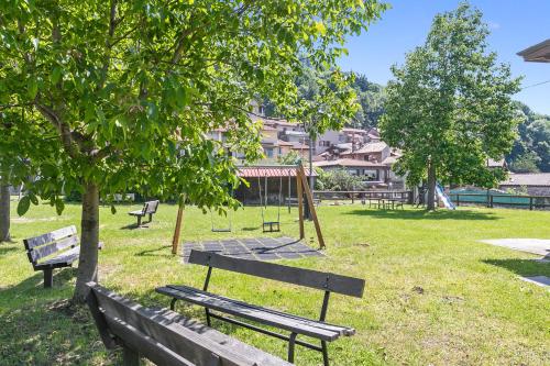 a park with benches and a table in the grass at Residenza Quadrifoglio in Casalzuigno