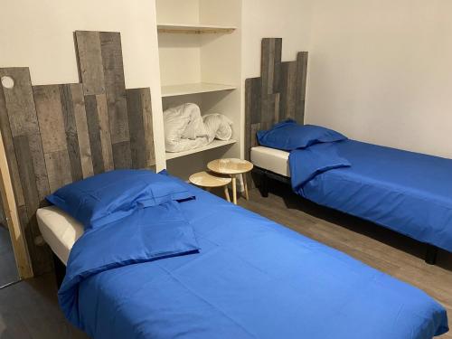 two beds in a room with blue sheets and a table at Maison spacieuse et agréable à 200m de la mer in Saint-Nazaire