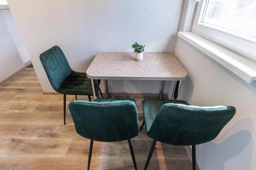 a table with four green chairs and a plant on it at Baba Yaga Treehouse in Meškiai