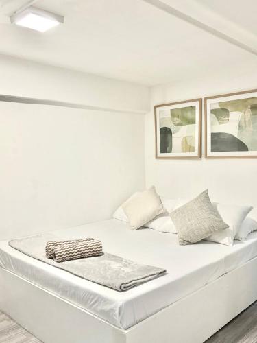 a white bed in a room with two pictures on the wall at Budget Loft-type condo in Uptown CDO in Cagayan de Oro