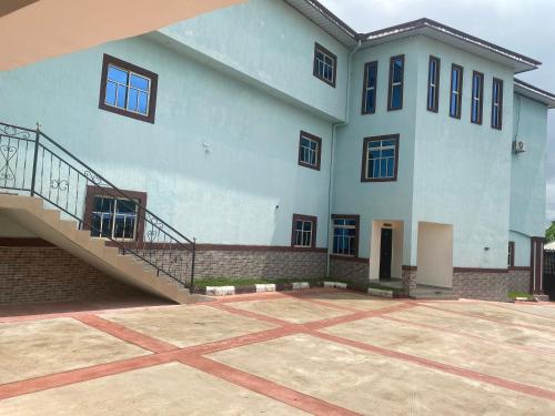 a large white building with a staircase in front of it at Beamgate Hotels & Apartments, Abak Rd, Uyo in Uyo