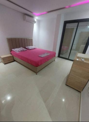 a bedroom with a pink bed in a room at Appartement à Khezama Est Sousse in Hammam Sousse