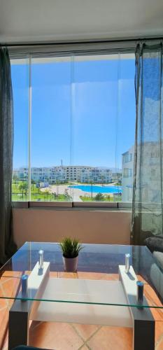 a glass table in a room with a large window at Superbe apartment en residence with pool in Cabo Negro
