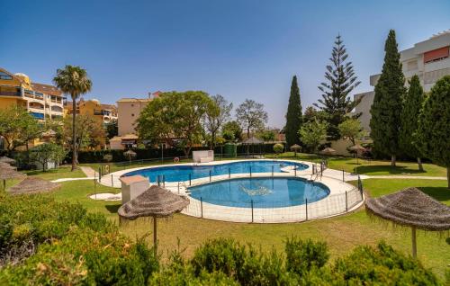 a swimming pool in a park with umbrellas at Awesome Apartment In Benalmadena in Benalmádena