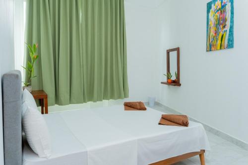 a white bed in a room with a green curtain at Villa 83 in Nedimale