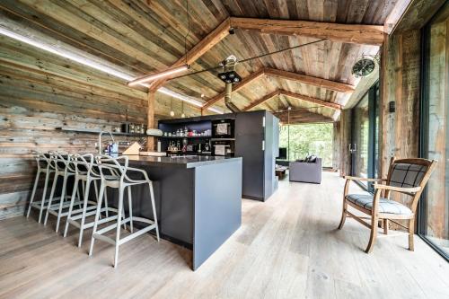 - une cuisine avec des murs en bois et un bar avec des tabourets dans l'établissement Chalet Bella, à Essert-Romand