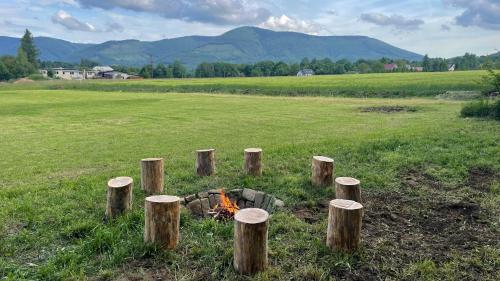 a group of wooden posts in a field with a fire at Apartmán pod Radhoštěm in Frenštát pod Radhoštěm