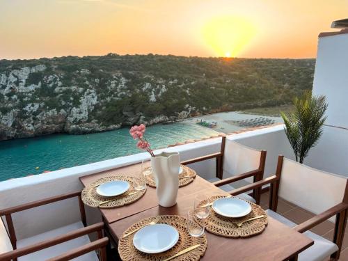a table with plates and flowers on a balcony with a view of the ocean at MiradorEnPorter - Nuevo - Vistas Increibles in Cala'n Porter