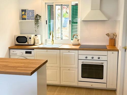 a kitchen with white cabinets and a sink and a microwave at MiradorEnPorter - Nuevo - Vistas Increibles in Cala'n Porter
