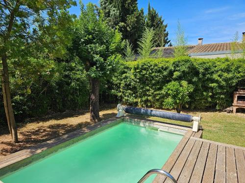 - une piscine dans une cour avec un banc en bois dans l'établissement Villa Caramel, à Saint-Quentin-la-Poterie