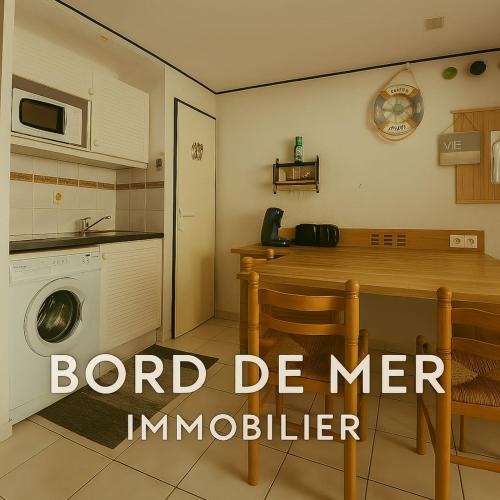 une cuisine avec une table et une machine à laver dans l'établissement Marine Escape, à Aresquies