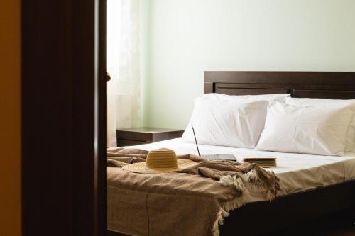 a bed with white pillows and a hat on it at Psatha Villa's in Psatha
