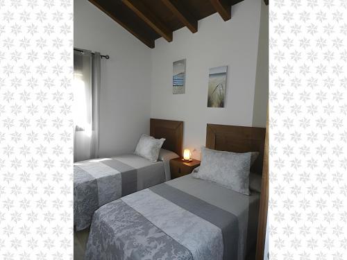 Dos camas en una habitación con paredes blancas. en Casa El Duque Leire, en Vejer de la Frontera