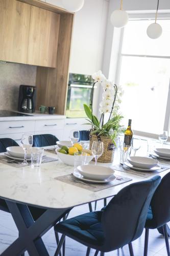 a dining room table with chairs and a white counter top at BURSZTYN - BERNSTEIN APARTMENTS in Dąbki