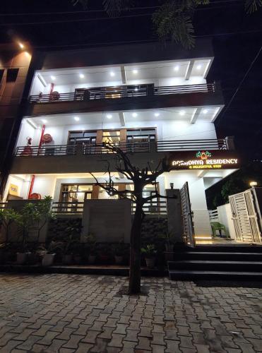 a building with a tree in front of it at Hotel Aaradhya Residency in Agra