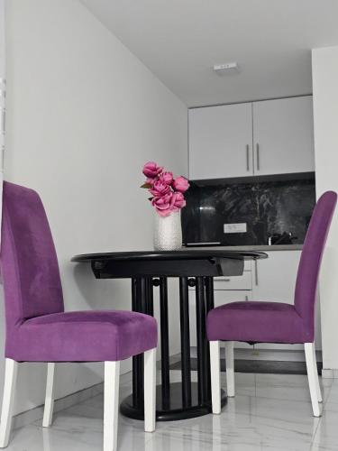 two purple chairs and a table with a vase of flowers at Studio Dana in Arandjelovac