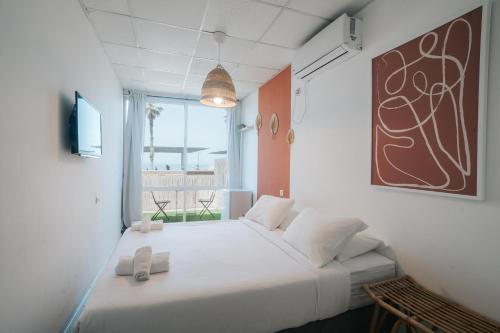 a white bed in a room with a window at מלון סנטרל ביץ תל אביב in Tel Aviv