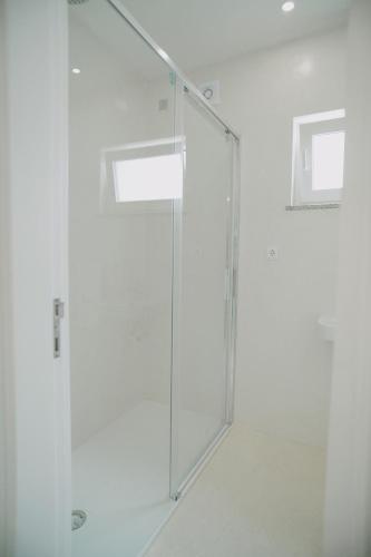 a glass shower door in a white room at Guest House Barrelas in Vila Nova de Paiva