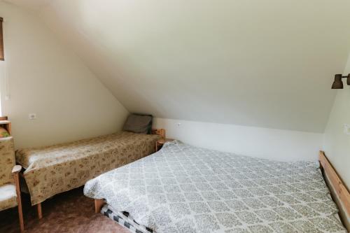 a small bedroom with a bed and a chair at Lejasbisenieki in Turaida