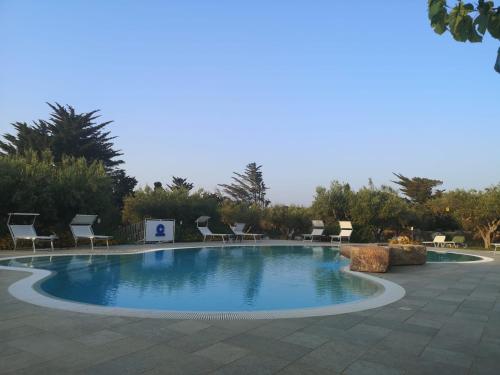 a large swimming pool with chairs around it at Casale la Macina Residence Scopello in Scopello