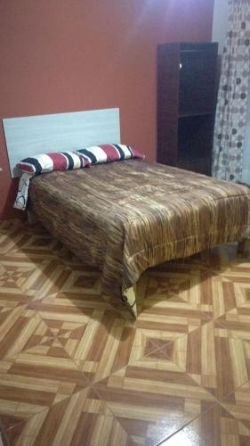a bed sitting on top of a wooden floor at Arum Qurpawasi Hospedaje in Cabanaconde