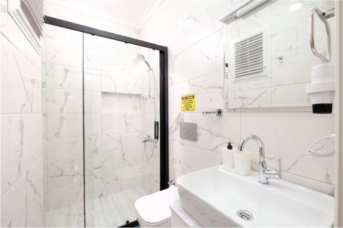 Un baño blanco con ducha y lavabo. en Roombnb Suıt, en Fethiye