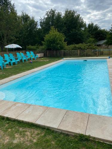 une grande piscine bleue avec des chaises et un parasol dans l'établissement Le Petit Chaumont Ecolodge, à Chaumont