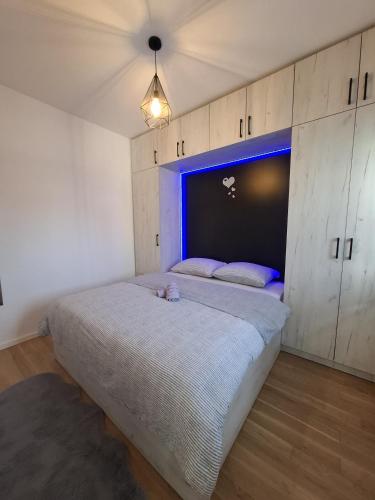 a bedroom with a large bed with a blue headboard at Apartman Sweet in Prijedor
