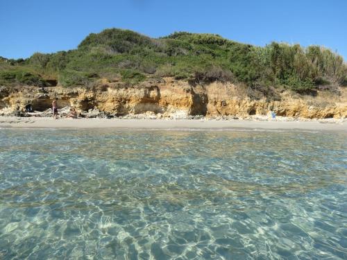 a beach with a person standing on the shore at Appartamento proprio sul mare! in Otranto